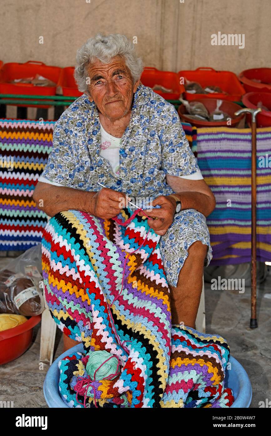 Alte griechische Frau knitzt bunte Teppiche, selbstgemachte Souvenirs, Limni Keriou, Insel Zakynthos, Griechenland Stockfoto