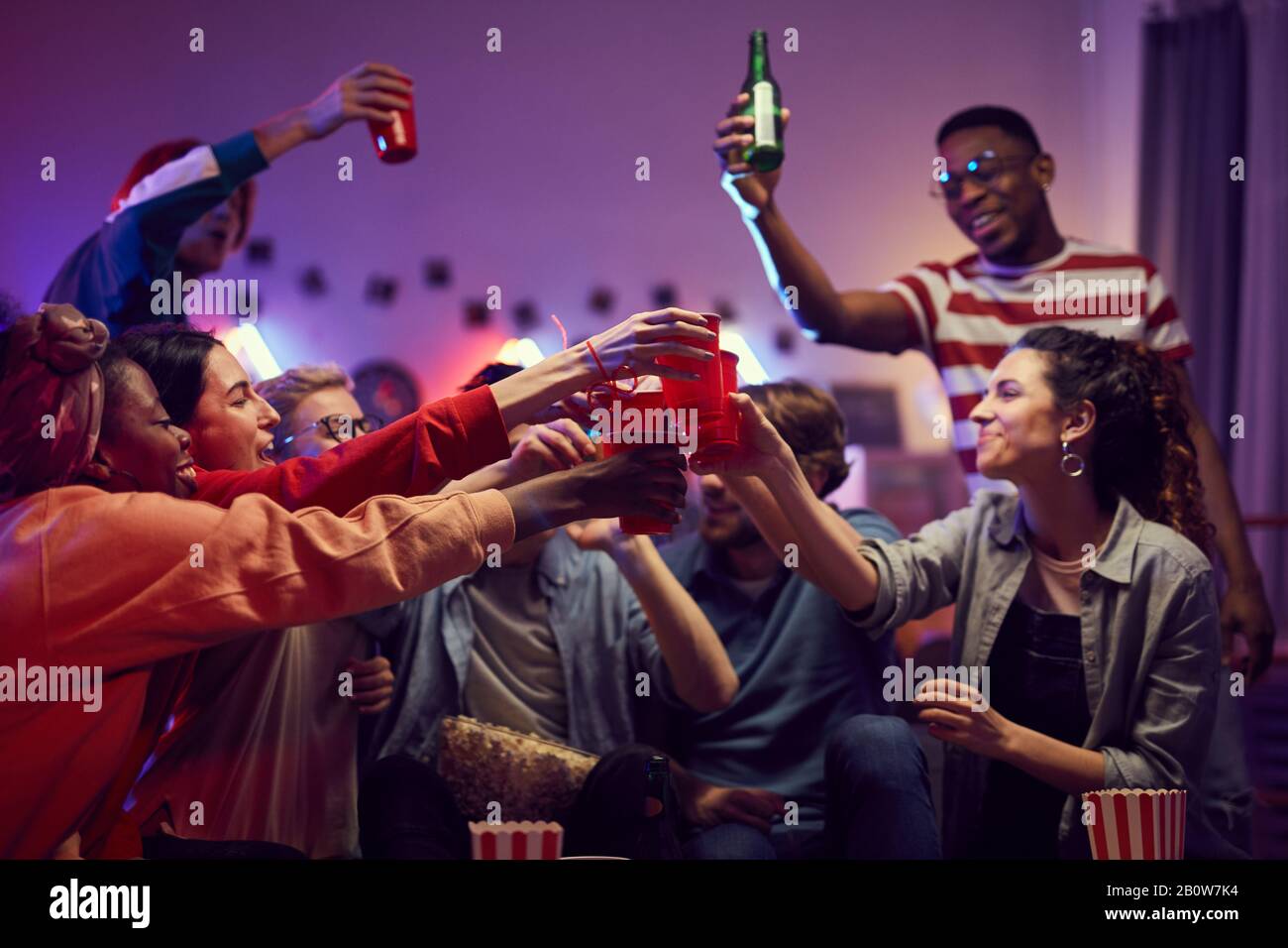 Eine Gruppe glücklicher Freunde, die Tassen und Biertöpfe halten, während sie zu Hause feiern Stockfoto