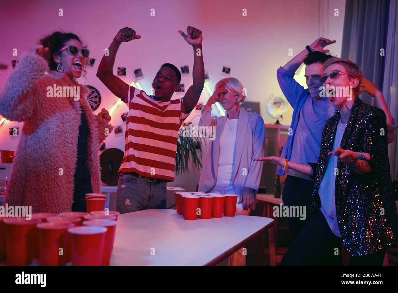 Junge aufgeregt schreiende und gestikulierende Leute, während sie auf der Party Bierpong spielen Stockfoto