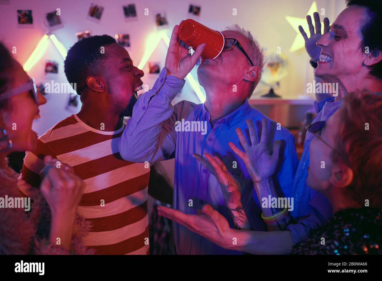 Senioren-Mann trinkt mit anderen Jugendlichen auf der Party Bier Stockfoto