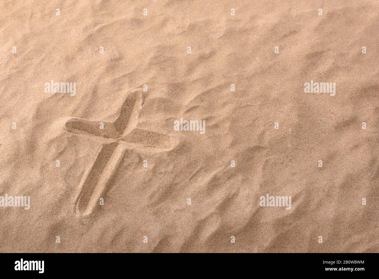 Kreuz als religiöses Symbol im Sand eingraviert. Horizontale Zusammensetzung Stockfoto
