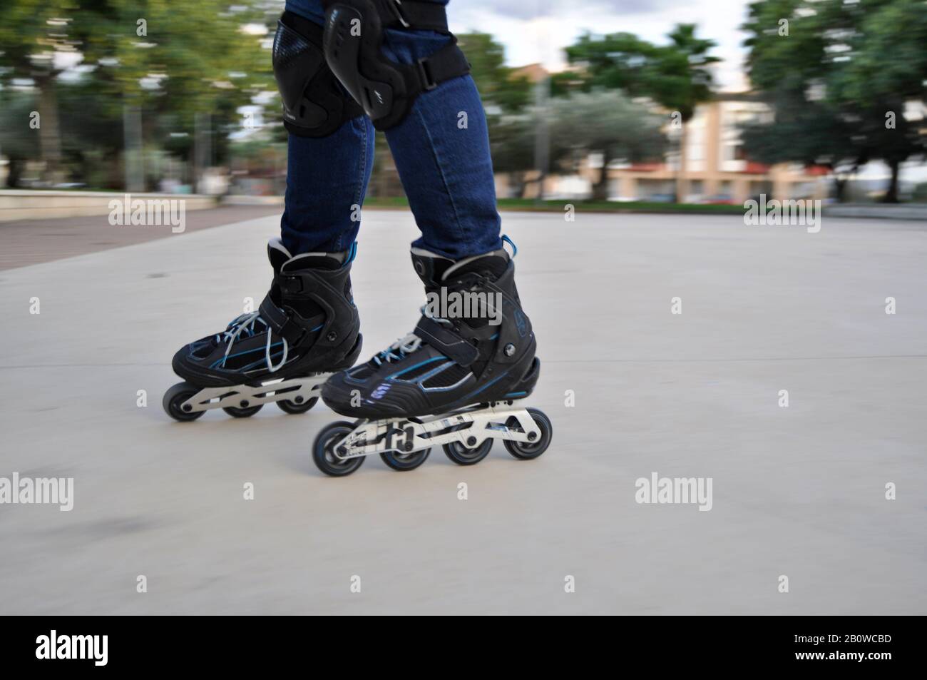 Beine des Mannes, der schwarze Inline-Skates auf einer Eislaufbahn im Freien trägt Stockfoto