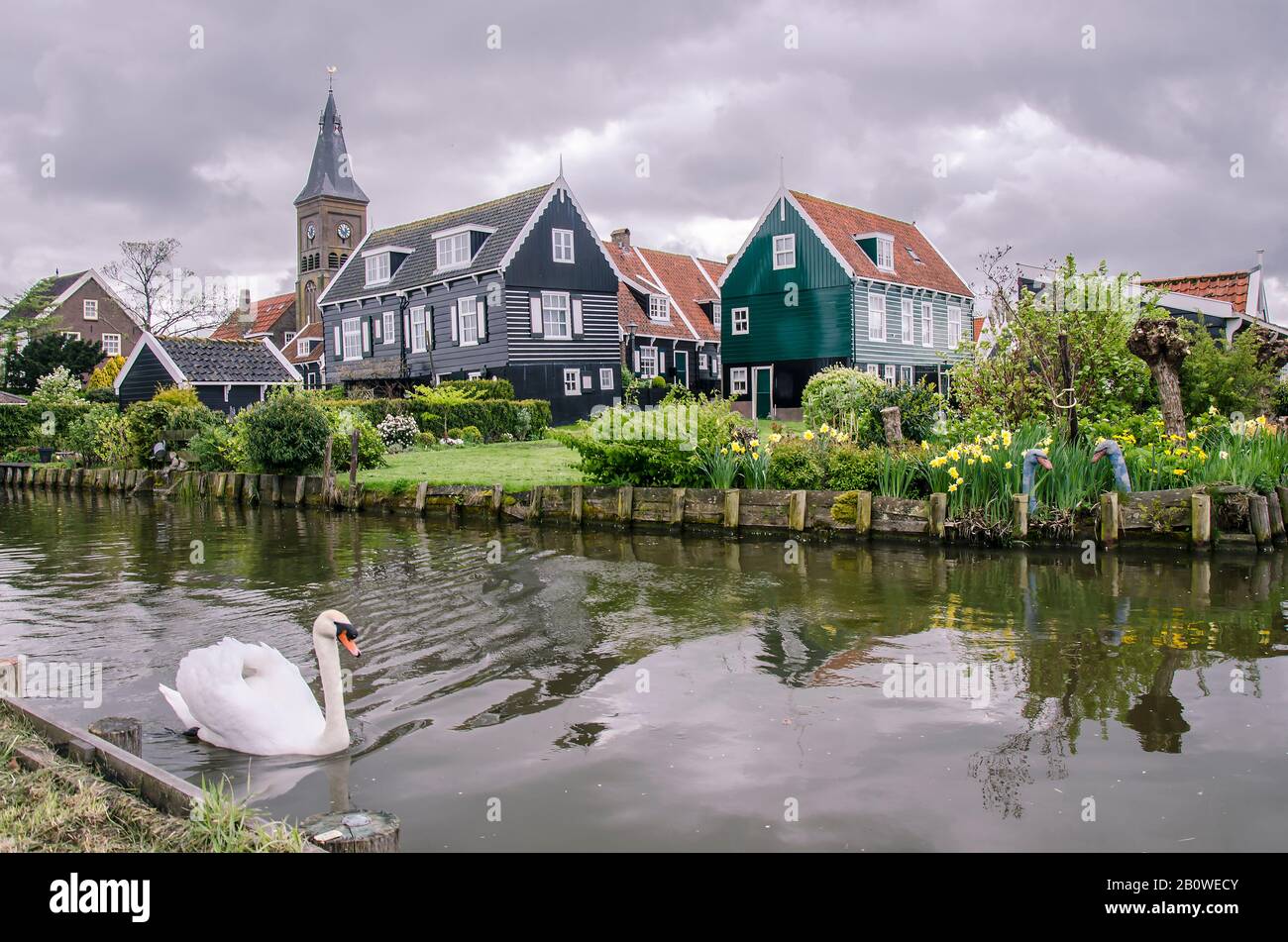 Traditionelle Fischerhäuser aus Holz, Kanal und Schwan, Marken, Niederlande. Blick auf Kanal, Brücke und traditionelle Fischerhäuser aus Holz im kleinen Dorf Stockfoto