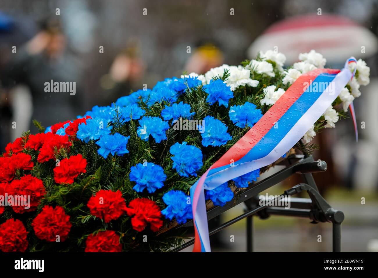 Flache Schärfentiefe (selektiver Fokus) Bild mit der russischen Flagge gefärbte Blumen auf einem Trauerkranz mit der russischen Fahne darauf während einer Regenda Stockfoto