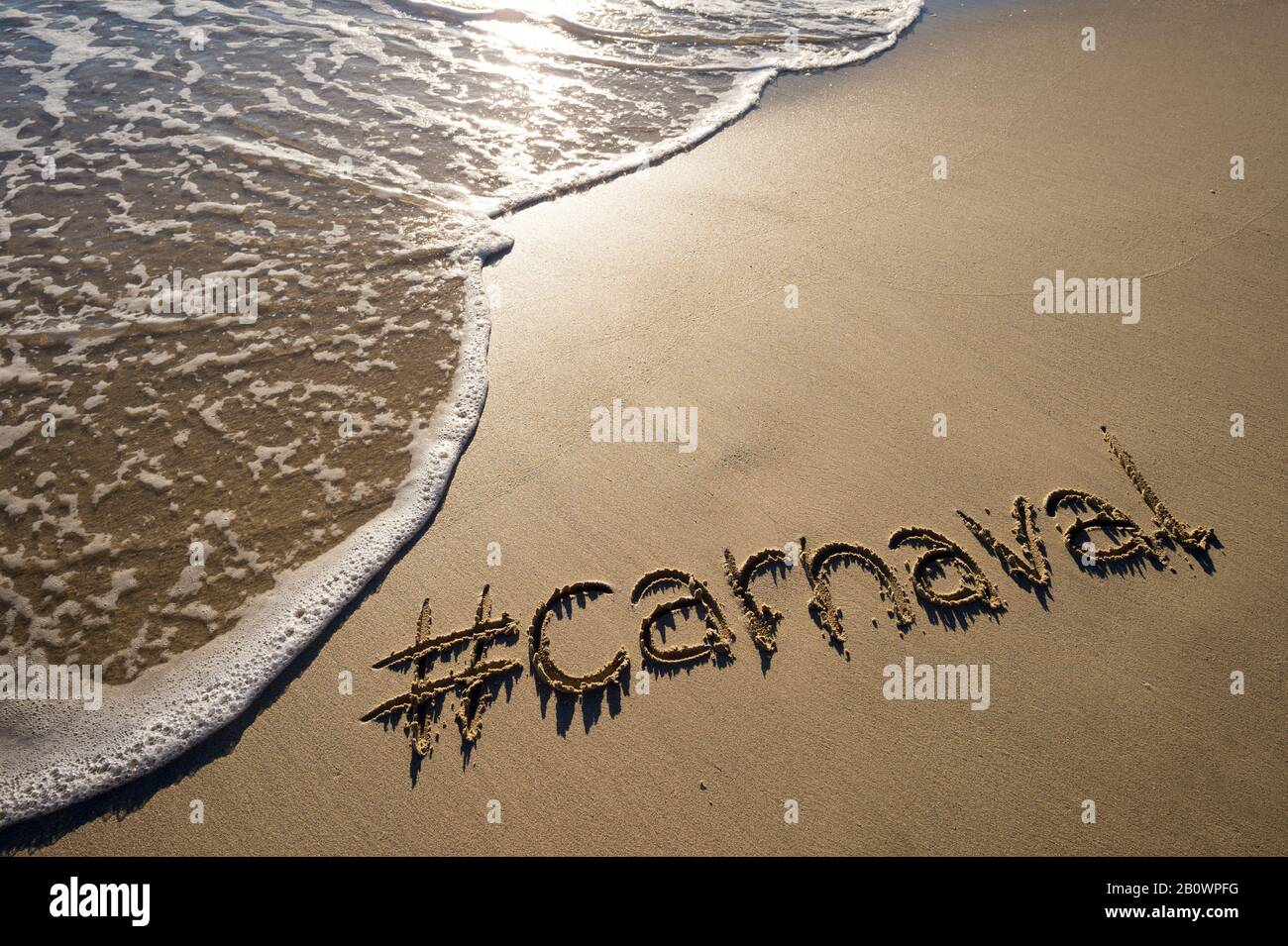 Moderne Botschaft für Karneval (portugiesisch für Karneval) mit einem sozialmedienfreundlichen Hashtag, der auf glattem Sandstrand geschrieben ist Stockfoto