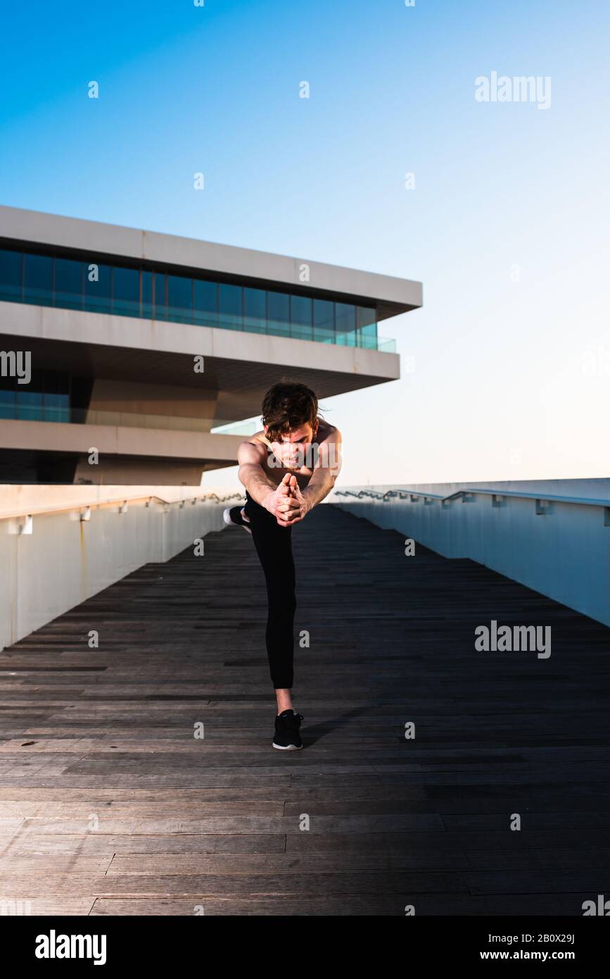 Junge Sportler, die artikuläre Bewegungen des Yogas in einem städtischen Gebiet der Stadt durchführen. Stockfoto Junge Sportler, die artikuläre Bewegungen des Yogas in einem städtischen Gebiet der Stadt durchführen. Stockfoto
