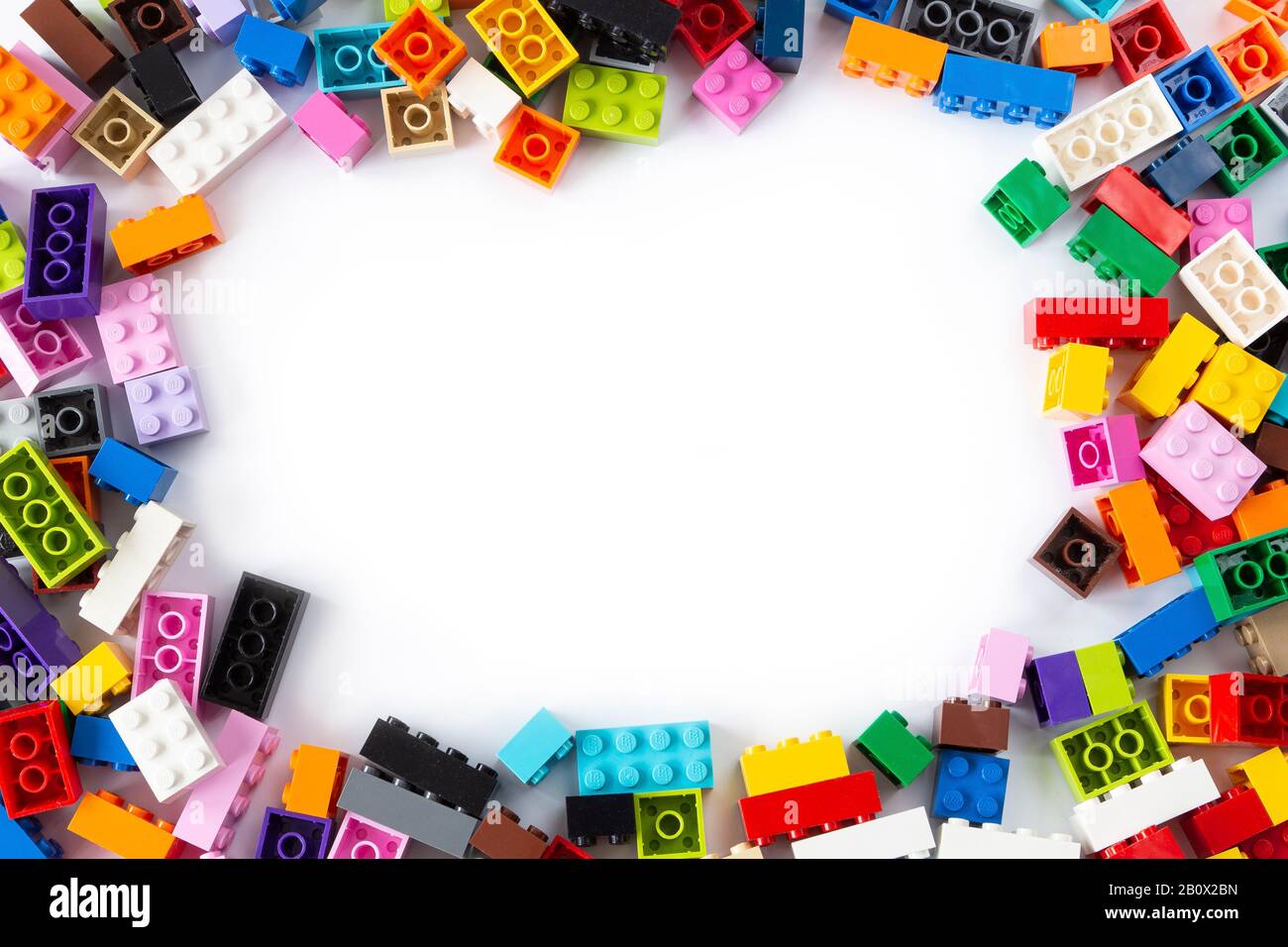 Nahaufnahme eines übereinandergelegten Haufens bunter Lego-Steine von oben mit Platz für Text in der Mitte. Isoliert auf weißem Hintergrund, Kopierbereich. Stockfoto