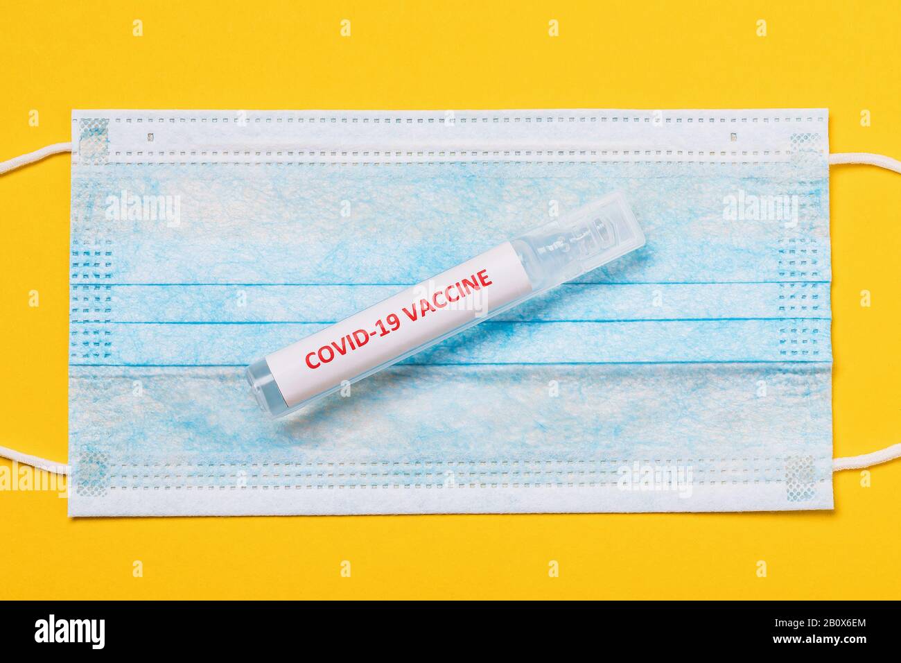 COVID-19 Coronavirus Impfstoff Ampulle auf medizinischer Maske, Draufsicht Stockfoto