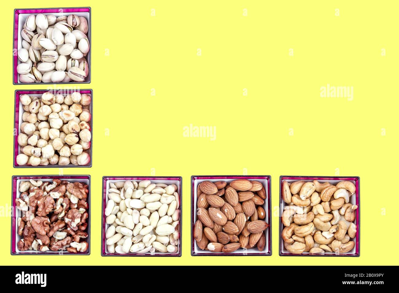 Verschiedene Nussarten: Erdnüsse, Cashews, Mandeln, Haselnüsse, Walnüsse und Pistazien auf gelbem Hintergrund, Copy Space Stockfoto