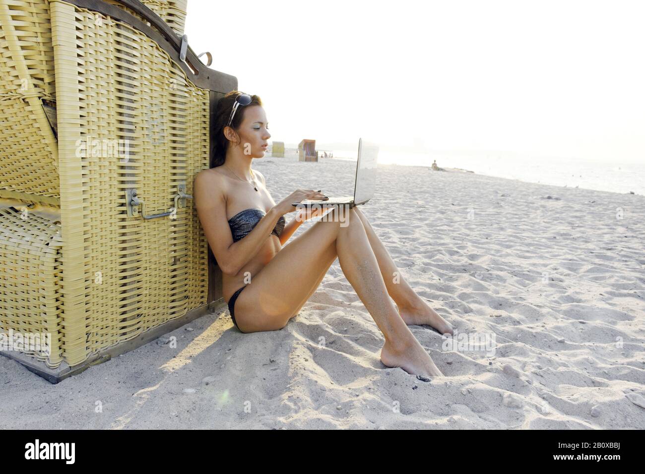 Junge Frau mit Laptop am Strand, Niendorf an der Ostsee, Schleswig-Holstein, Deutschland, Stockfoto