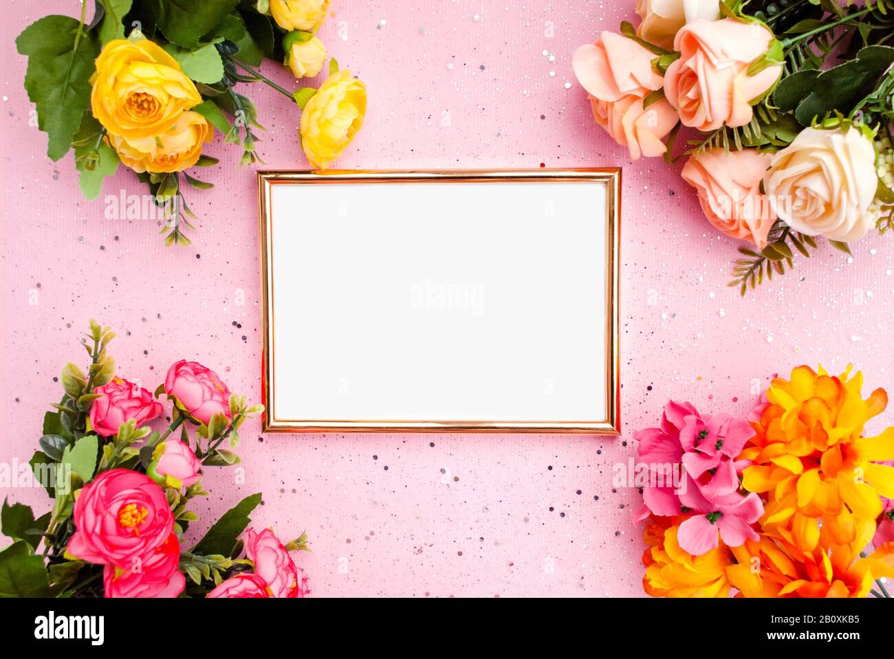 Goldener Rahmen für Fotografie, Blumen, rosafarbener Hintergrund mit Glitzereffekt. Flach, lat. Draufsicht. Platz für Text Stockfoto