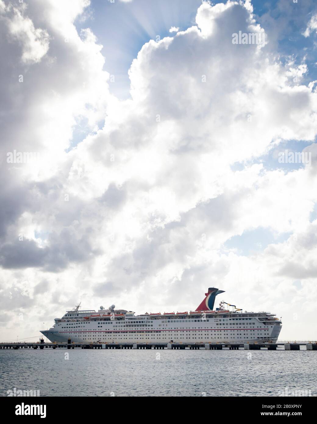 Fernblick auf das Kreuzfahrtschiff "Carnival Fantasy", am Hafen in Cozumel unter hellem bewölktem Himmel Stockfoto