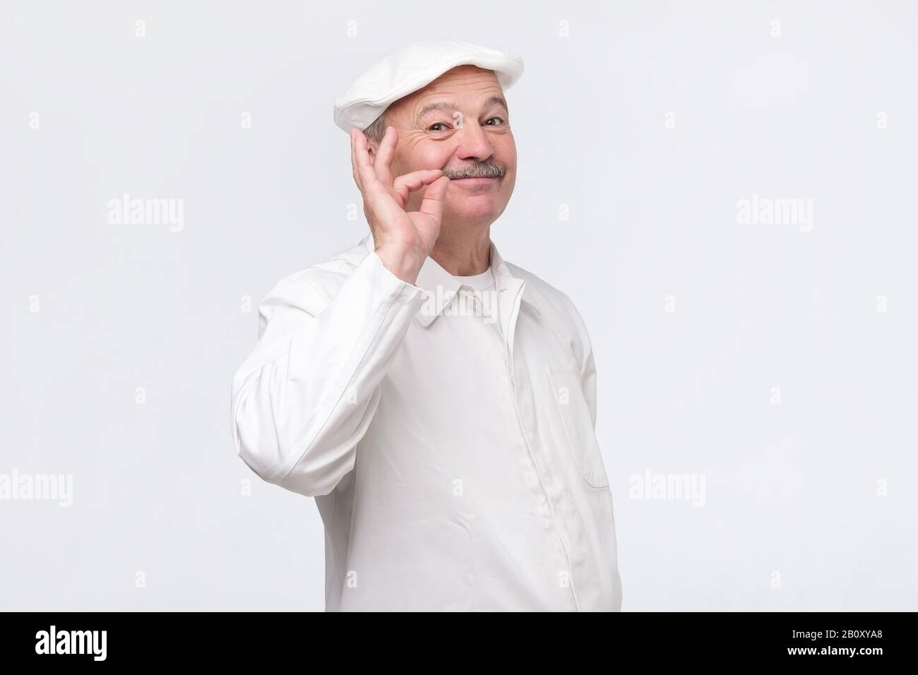 Kochen, Essen, Beruf und Gesten-Konzept. Lächelnder Chefkoch, der das Zeichen in Ordnung zeigt. Professioneller Koch in weißer Uniform, gestikulierend ausgezeichnet. Stockfoto