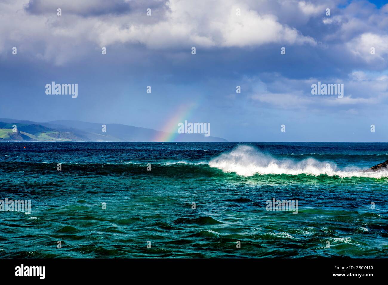 Apollo Bay mit Regen, der sich nähert und einen kleinen Regenbogen über dem Wasser bildet. Victoria, Australien Stockfoto