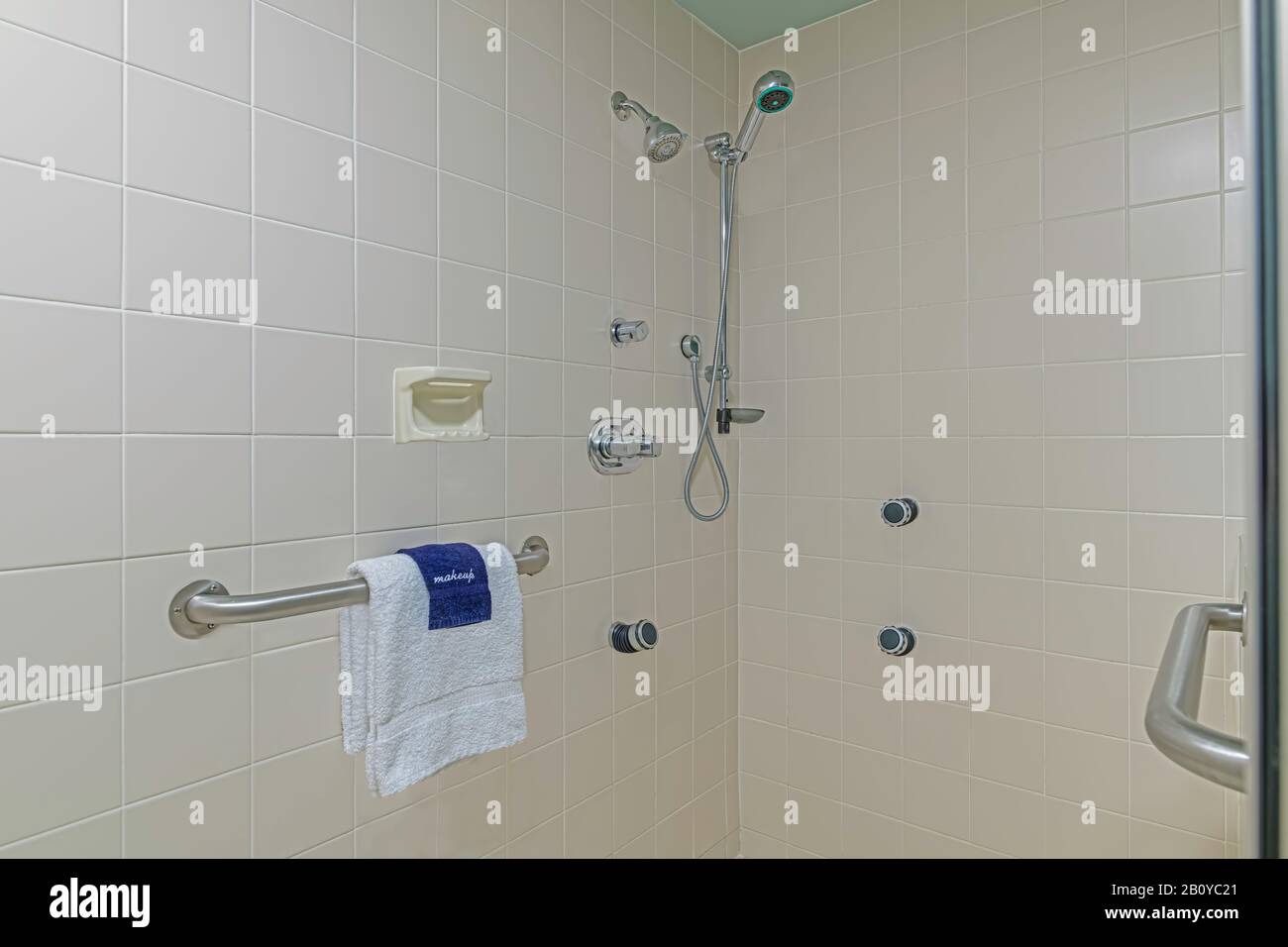Geflieste Dusche mit Handtüchern und Handlauf Stockfoto