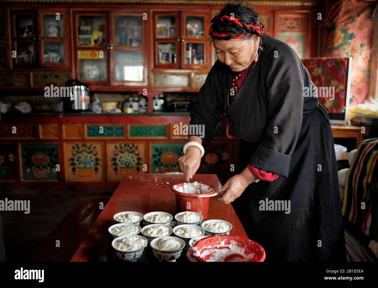 Eine Tibeterin bereitet Schalen mit Yakjoghurt für die Lamas, das tibetische Plateau, vor Stockfoto