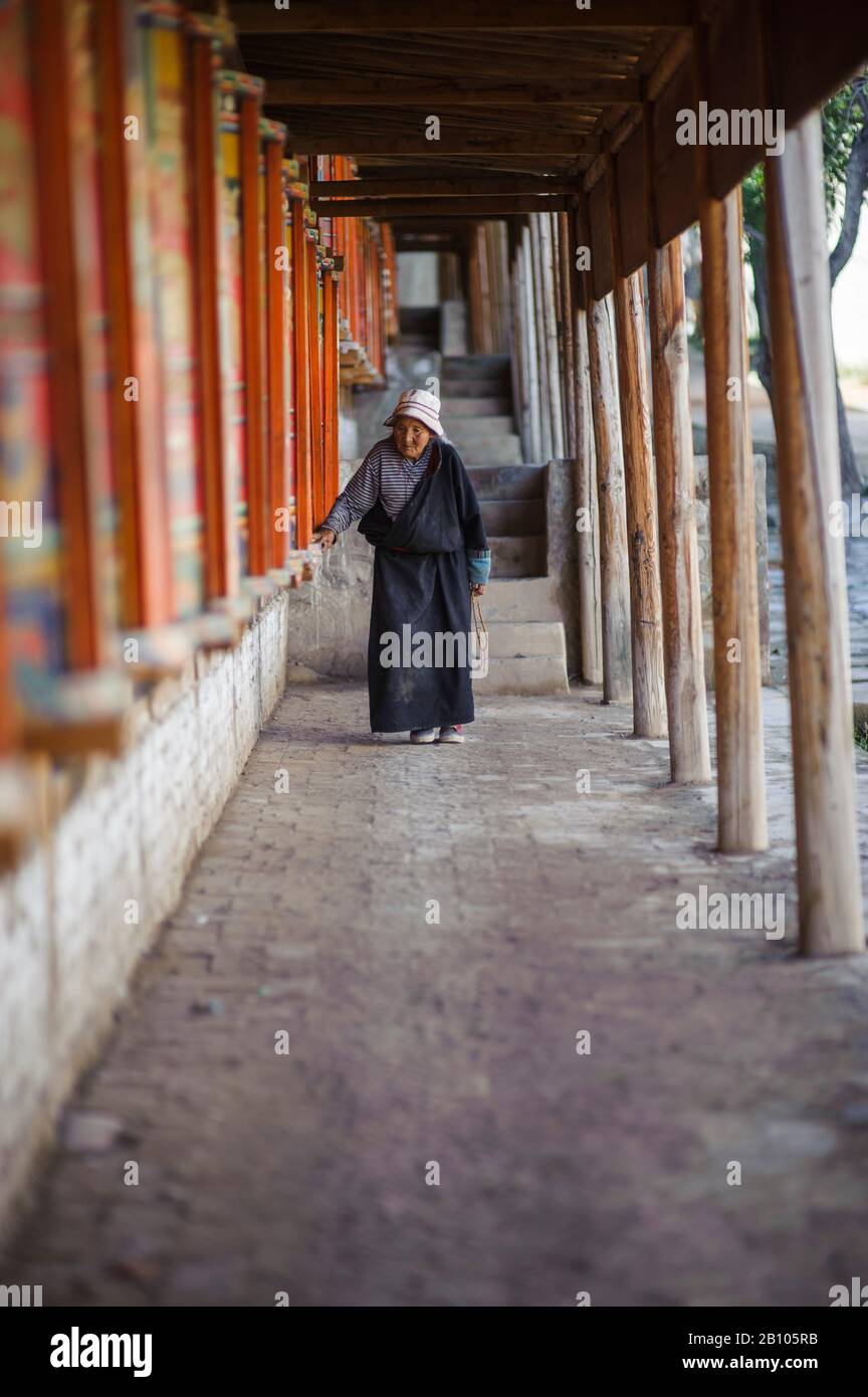Tibeterin dreht tibetische Gebeträder, Kloster Rebkong, Tongren, China Stockfoto