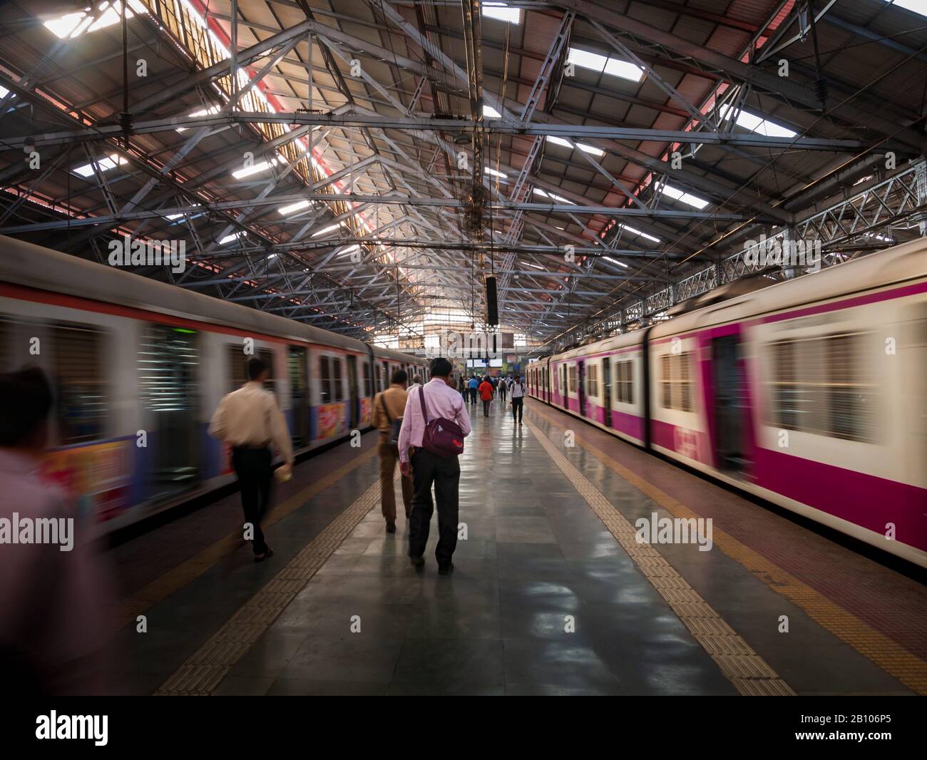 Mumbai, Indien - 18. Dezember 2019: Unidentifizierte Passagiere, die zu Fuß unterwegs sind, und Züge aus Mumbai, die am CST-Bahnhof, einem der verkehrsreichsten S-Bahn-Stationen, schnell fahren Stockfoto