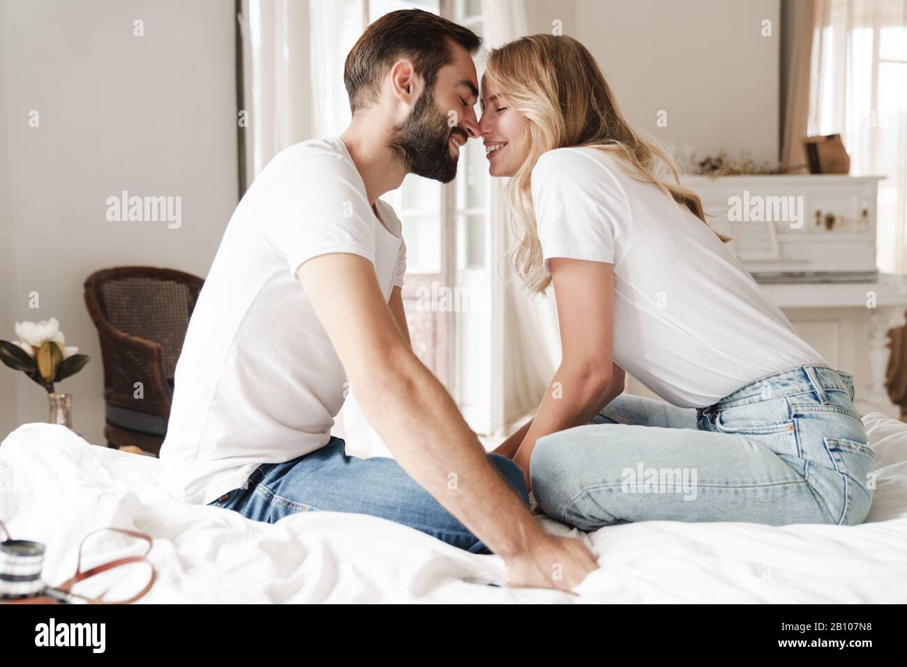 Schönes glückliches junges Paar, das sich zuhause im Bett erholt und umarmt Stockfoto