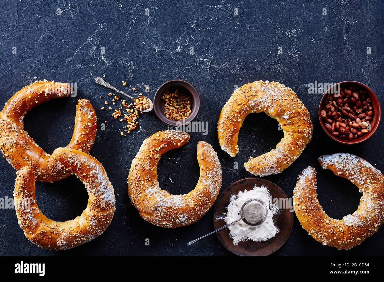 Österreichische Süßgebäckerrollen mit Erdnüssen und Puderzucker auf dunklem Betonhintergrund, Draufsicht, Kopierraum bestreut Stockfoto