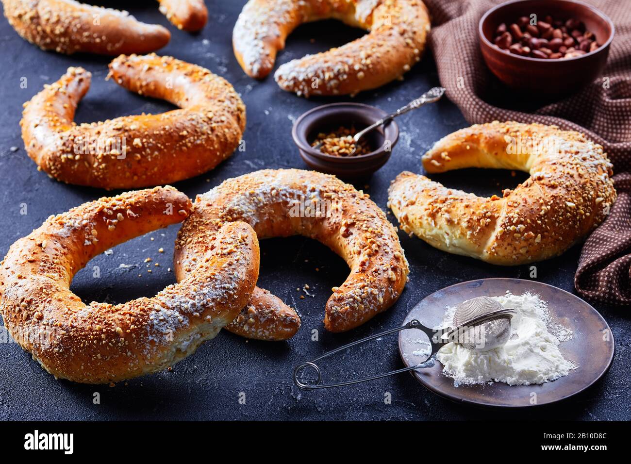 Traditionelle süße Gebäckrollen kifli oder kipfel bestreut mit Erdnüssen und Puderzucker auf dunklem Betongrund, Nahaufnahme Stockfoto