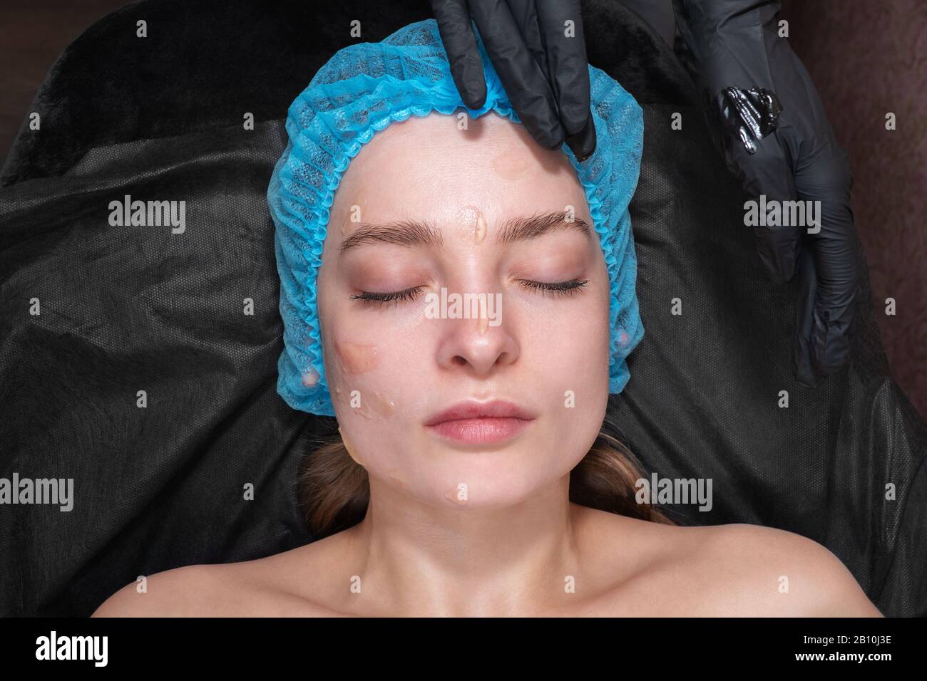 Kosmetikerinnen verschmieren Salbe auf dem Gesicht Stockfoto