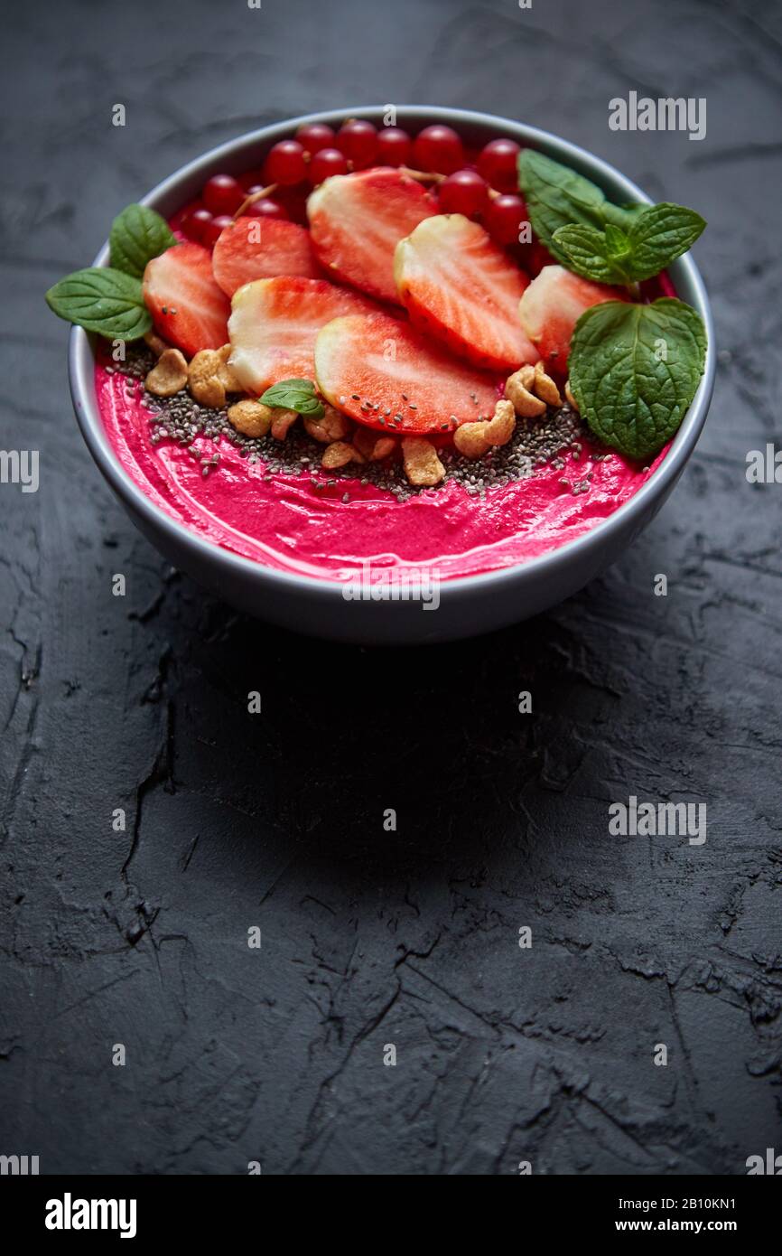 Sommerbeere Smoothie oder Joghurt Schüssel mit Erdbeeren, roten Korinten und chia Samen auf schwarz Stockfoto