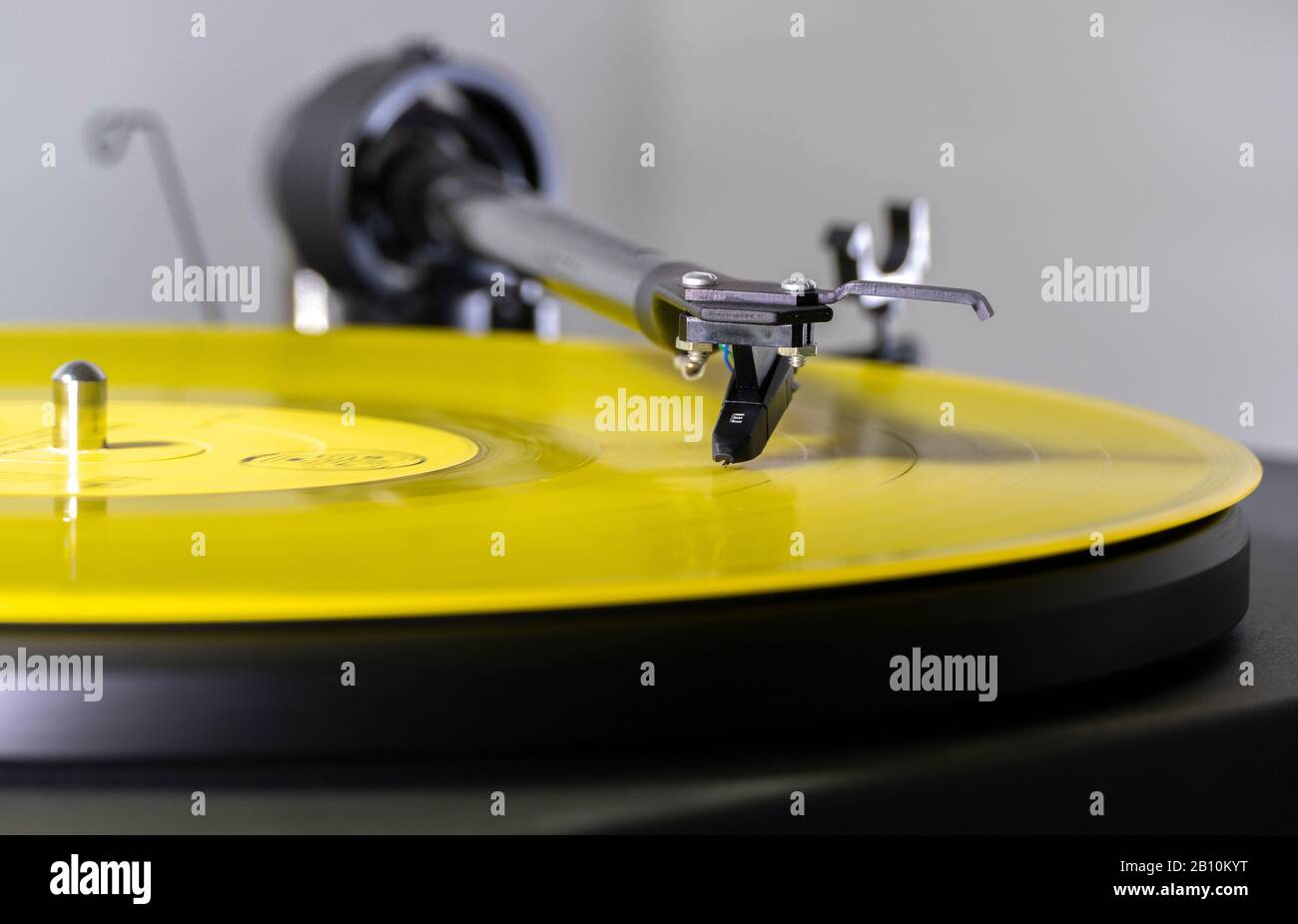 Die Nadel/der Stift auf den Rillen einer gelben Vinyl-LP-Schallplatte, auf einem drehenden Plattenspieler, der einen Musikalbum-Track wiedergibt. Stockfoto