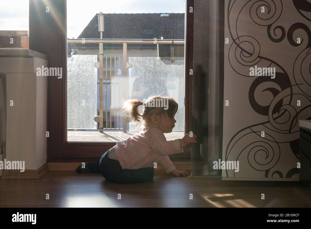 Kleines Mädchen schaut auf die Vorhänge im Wohnzimmer Stockfoto