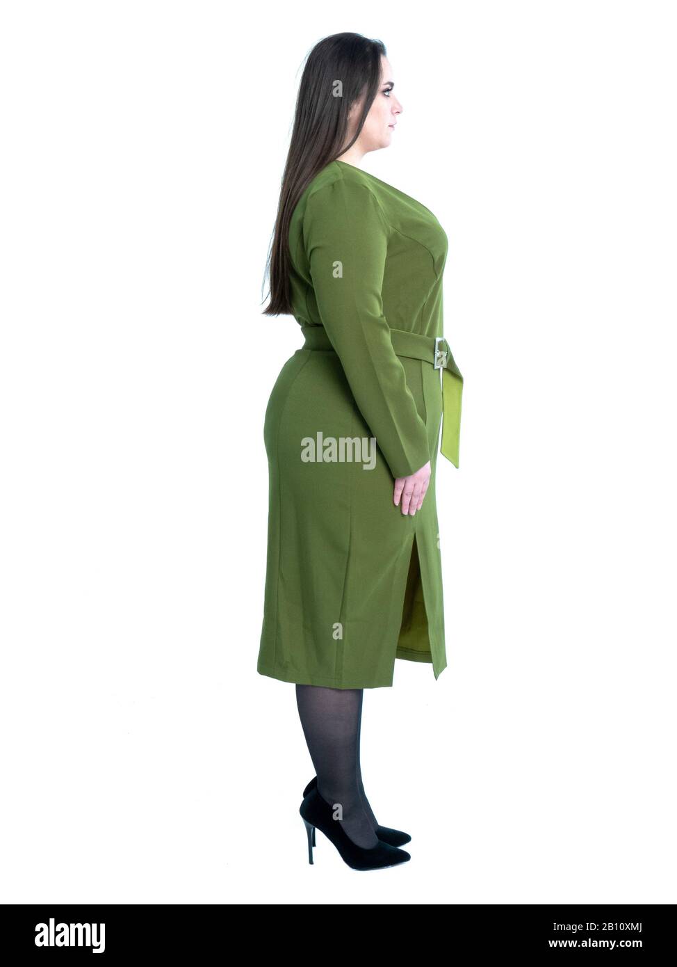 Plus Größe Frau in grünem Kleid posin wie Modell im Studio. Modelltests, Seitenansicht. Stockfoto