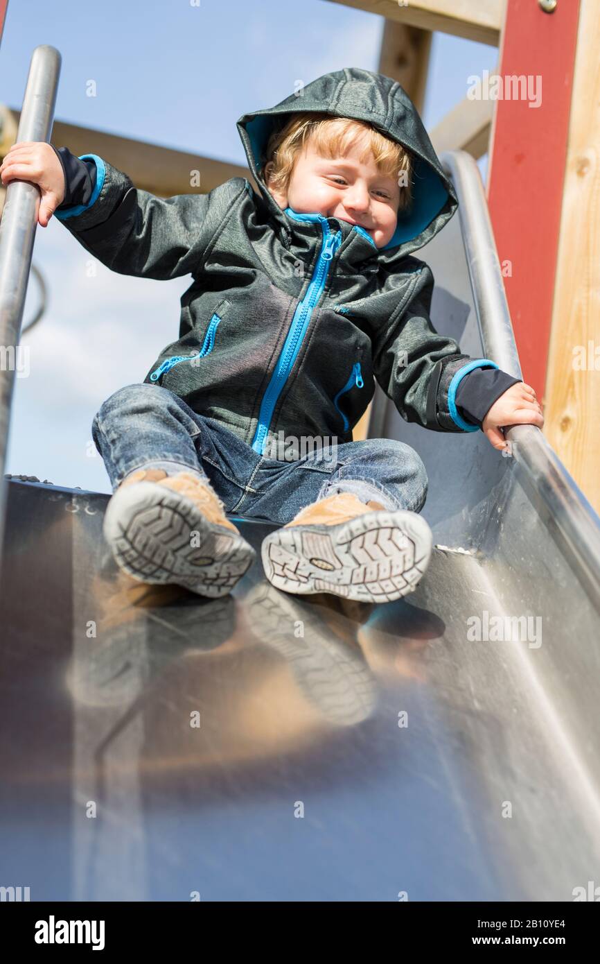 Kleiner Junge mit Kapuze auf Rutsche Stockfoto