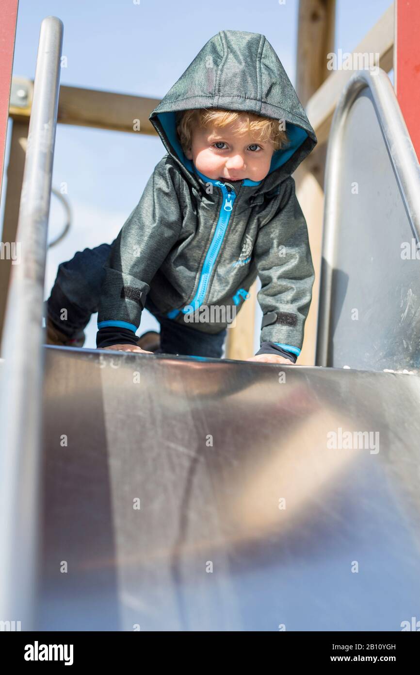 Kleiner Junge mit Kapuze auf Rutsche Stockfoto