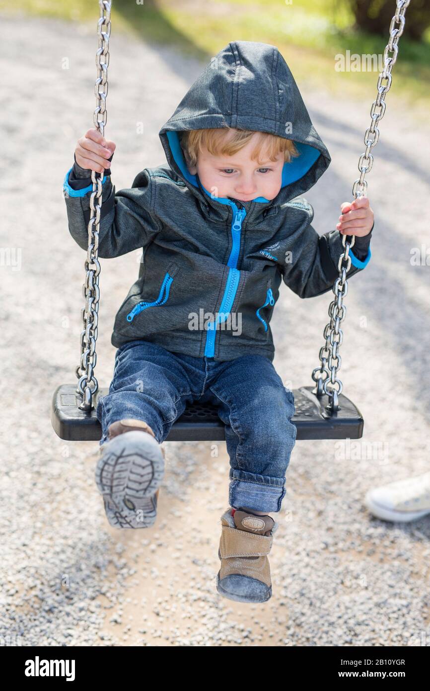 Kleiner Junge mit einer Haube auf einer Schaukel Stockfoto