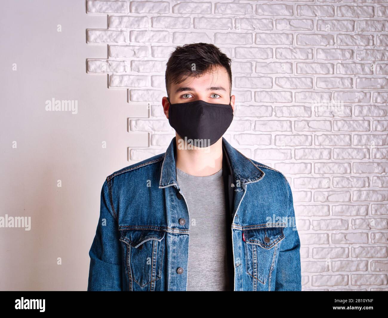Junger Mann in medizinischer Maske gegen weiße Wand Stockfoto