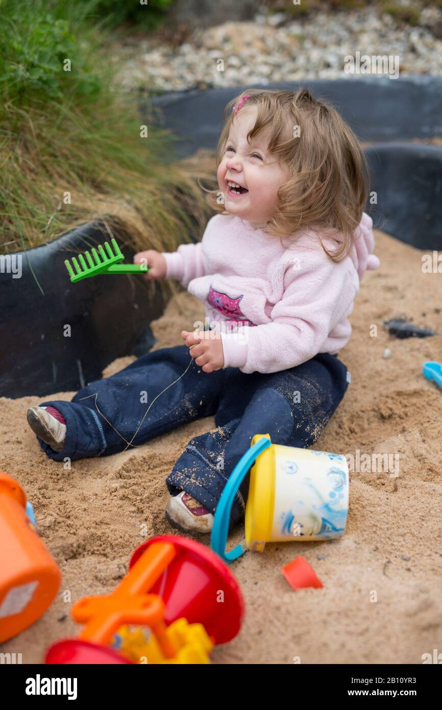Kleines Mädchen spielt im Sandkasten Stockfoto