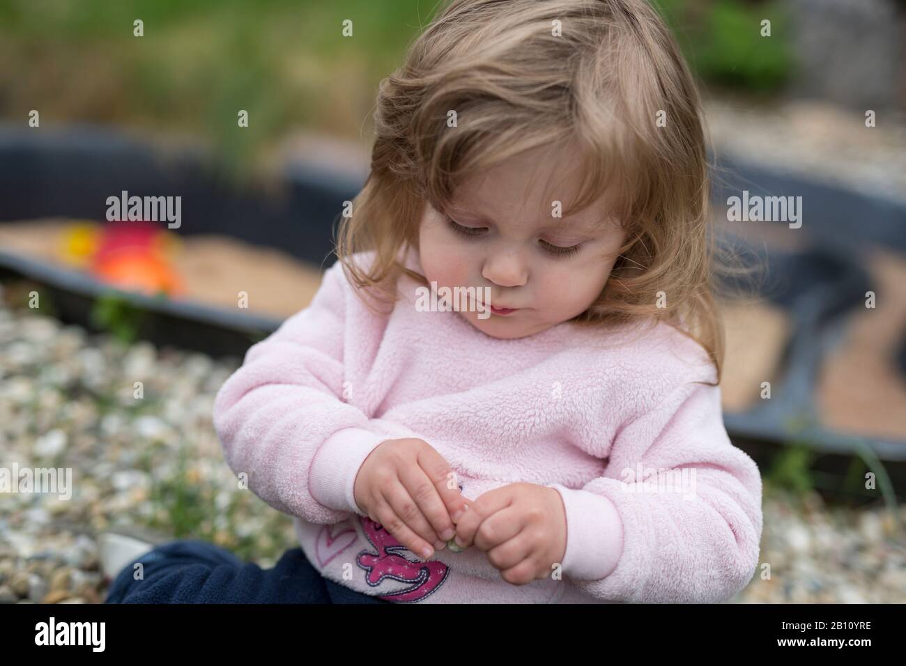 Kleines Mädchen spielt mit Blumen im Garten Stockfoto