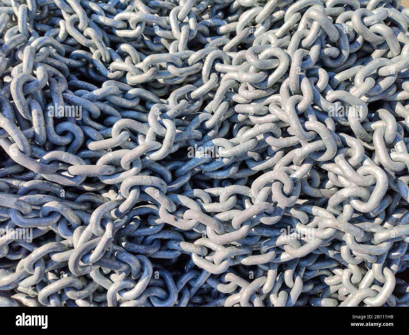 Hintergrundtextur der Ankerkette. Schwerer Industrie-Metallkettenhaufen, Draufsicht. Schiffsanlegestelle, Hafen, Hafenanlagen Stockfoto