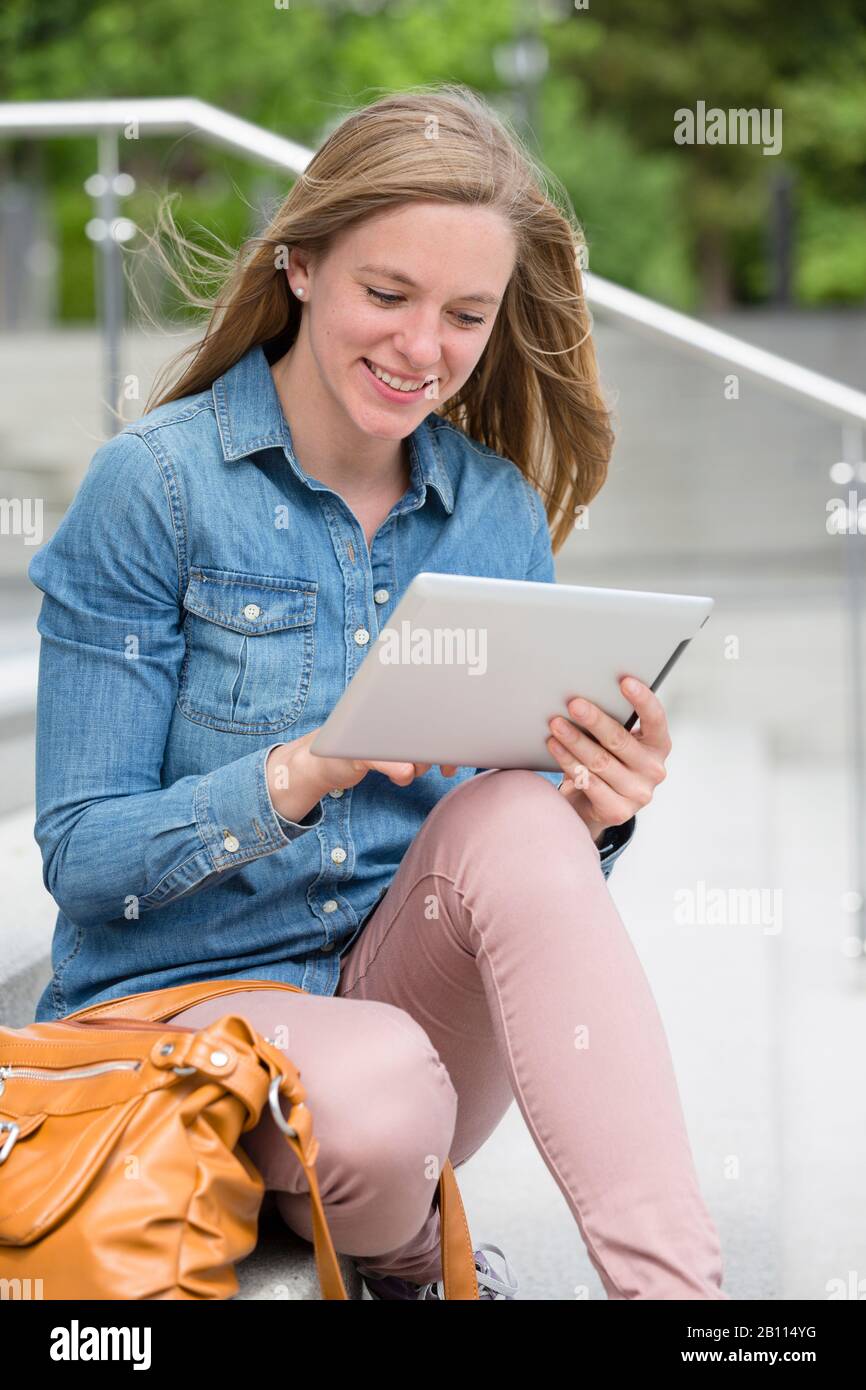 Frau sitzt auf einer Treppe und benutzt einen Tablet PC Stockfoto