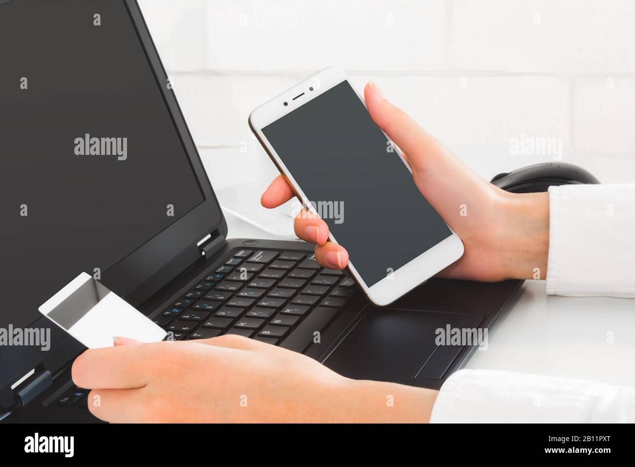 Online-Zahlung über Laptop und Mobiltelefon. Hände, die Kreditkarten und mobile Geräte halten, um Online-Transaktionen durchzuführen. Business Mockup Stockfoto