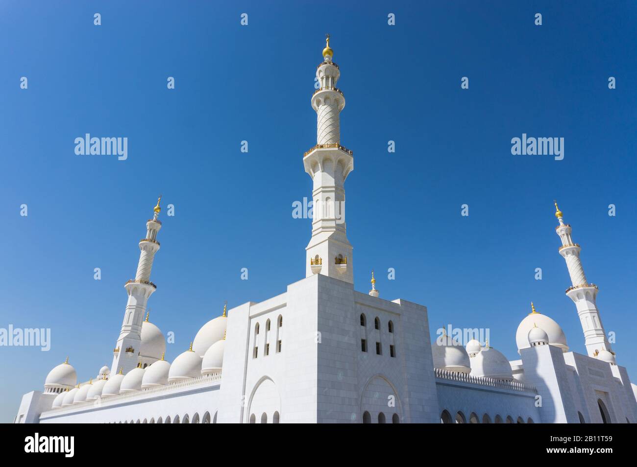 Markante weiße Minarette und Kuppeln der Scheich Zayad Grand Moschee, gegen einen strahlend blauen Himmel. Stockfoto