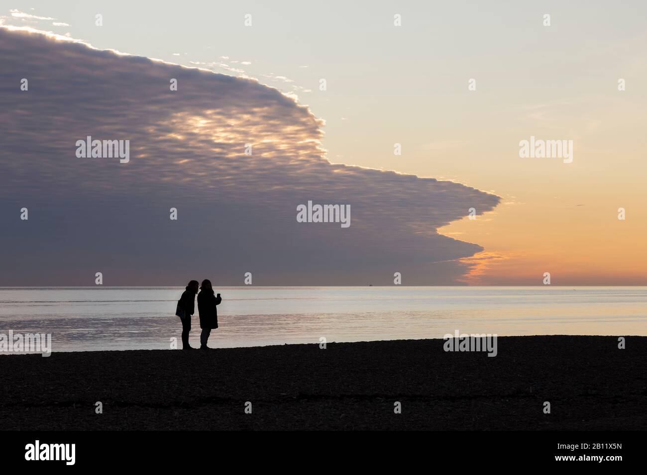 Silhouette von Frauen, die am Strand in Brighton sprechen Stockfoto