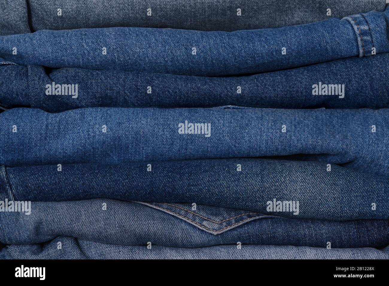 Jeans-Stapel in Denimblau, in klassischem Indigo-Stil in verschiedenen Farben. Nahaufnahme, Modekonzept, Hintergrund. Stockfoto