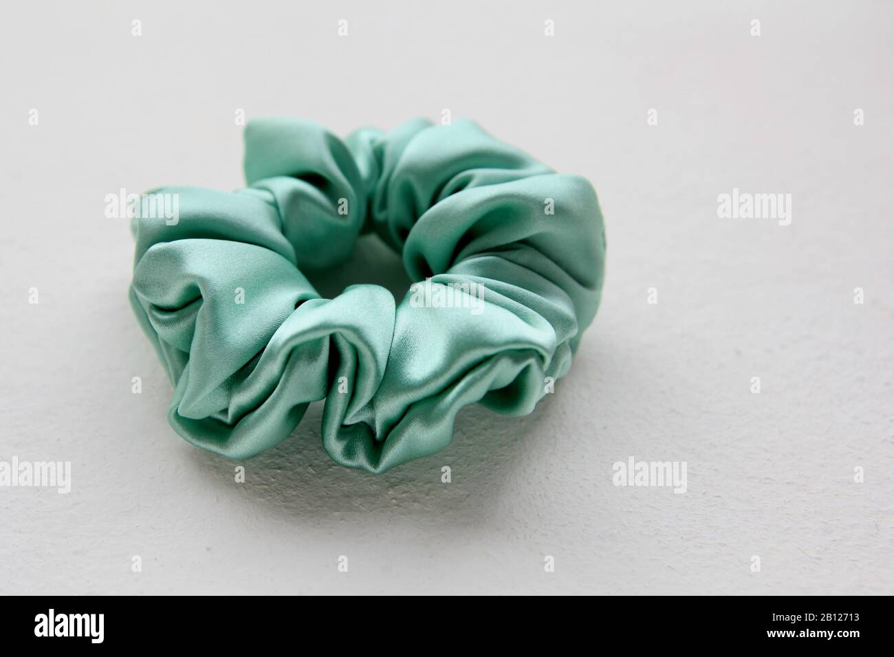 Türkisfarbenes Seiden-Schnuppchen isoliert auf weißem Hintergrund. Flat Lay Haarkleiderool mit Farbenfrohem Elastischem Haarband, Bobble Scrunchie Haarband Stockfoto