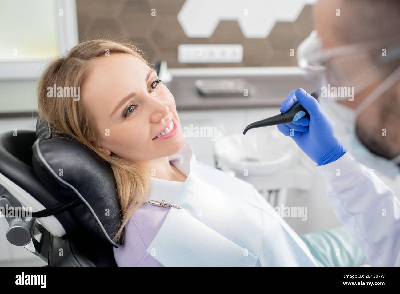 Hübsche junge blonde Frau mit dem Kopf auf schwarzem Lederpolster Stockfoto