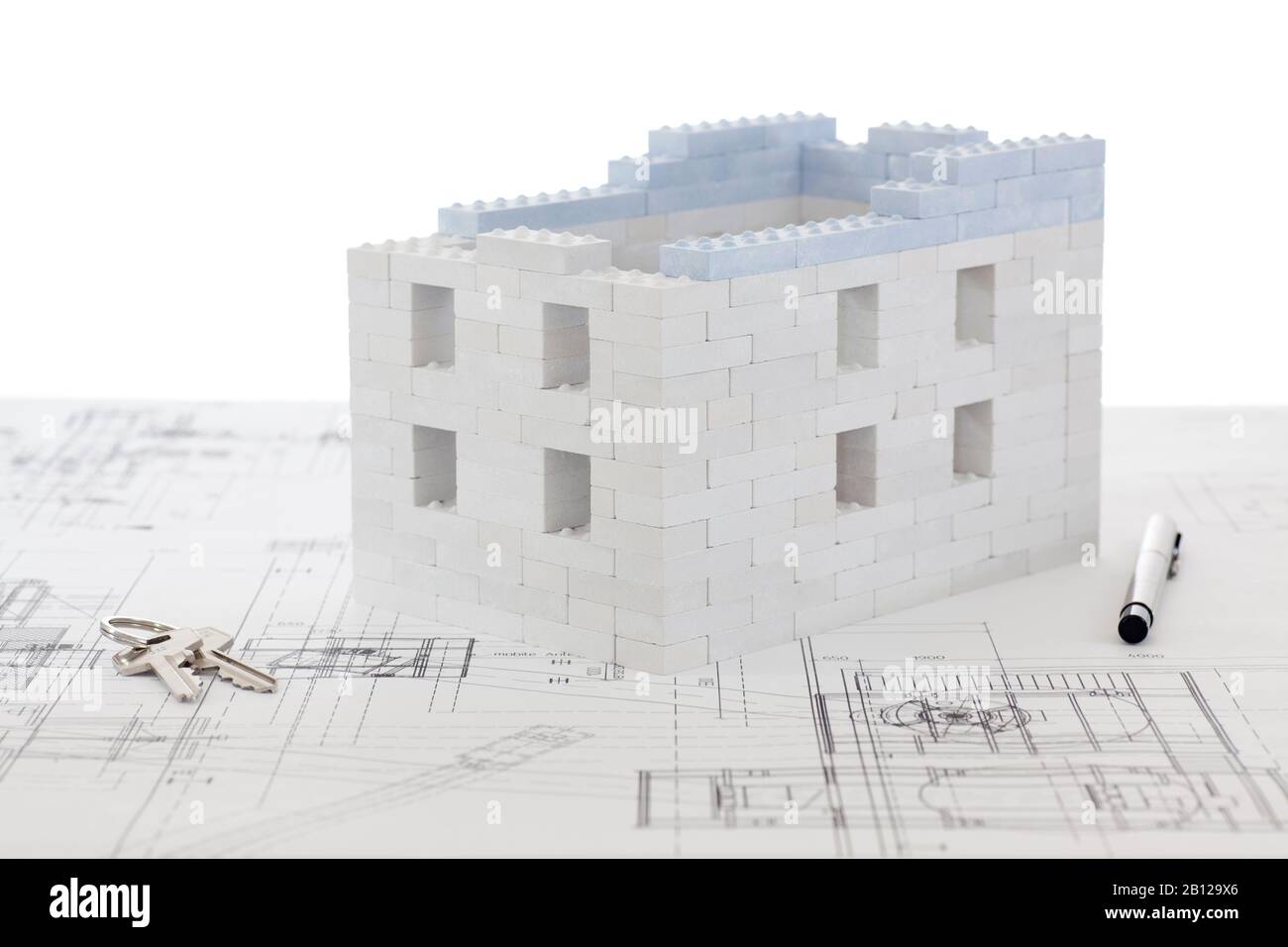 Haus aus Spielzeugblöcken mit Tasten und Stift auf Bebauungsplan - weißer Hintergrund Stockfoto