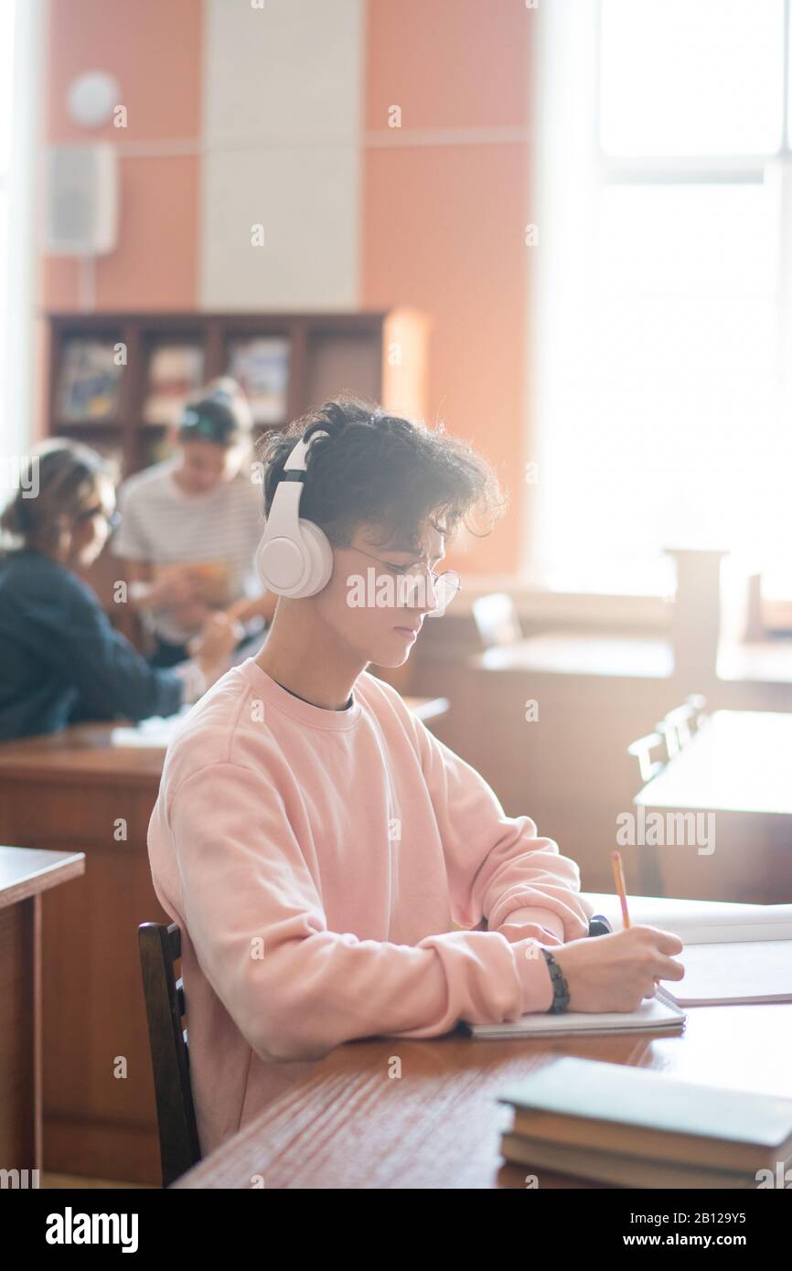 Ernsthafte Studenten mit Kopfhörern, die sich auf die Erstellung eines Berichtsplans konzentrieren Stockfoto