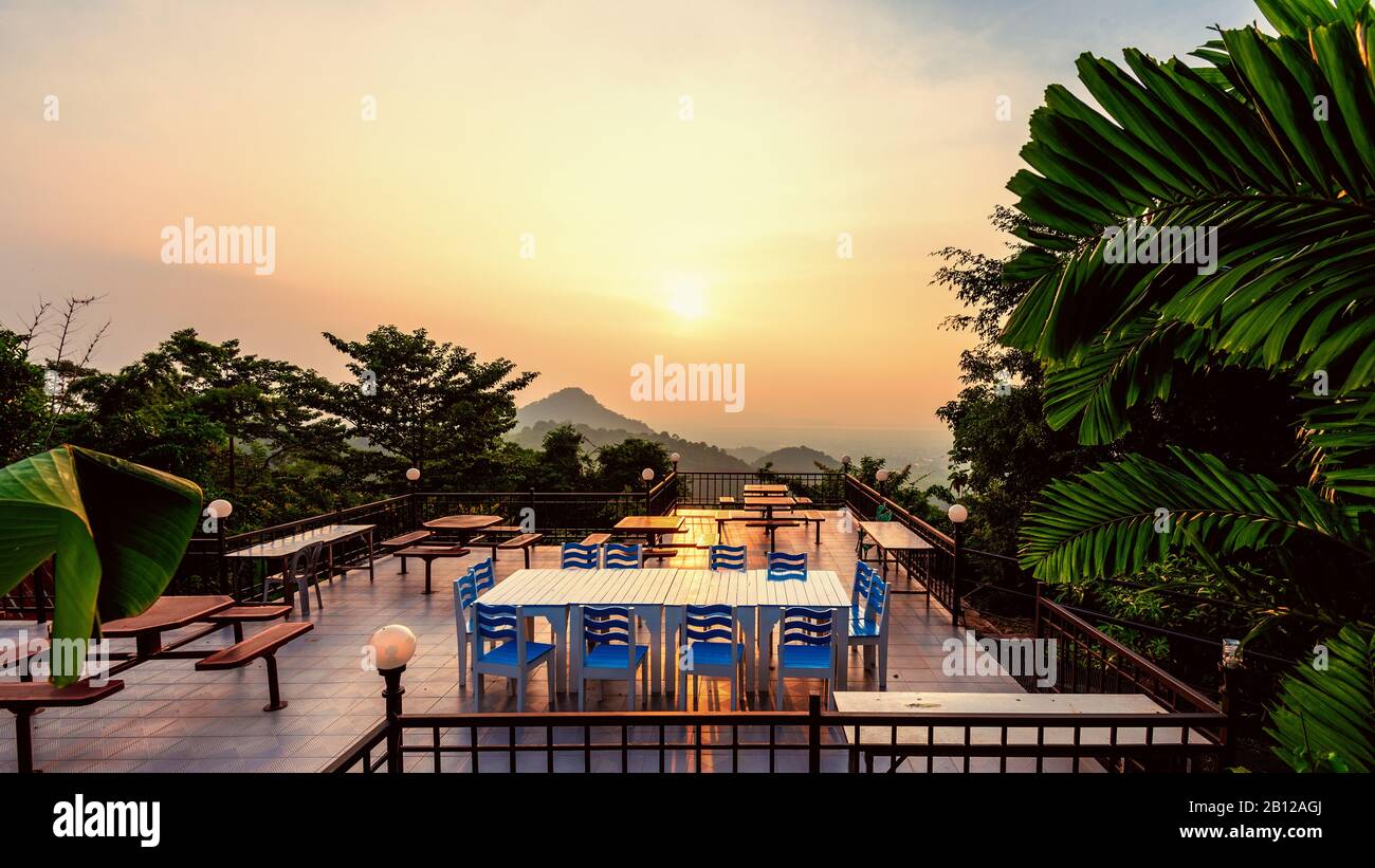 Hoher Aussichtspunkt für die schöne Naturlandschaft farbenfroher Himmel während des Sonnenuntergangs. Tisch und Stühle auf der Terrasse zum Speisen der Res Stockfoto