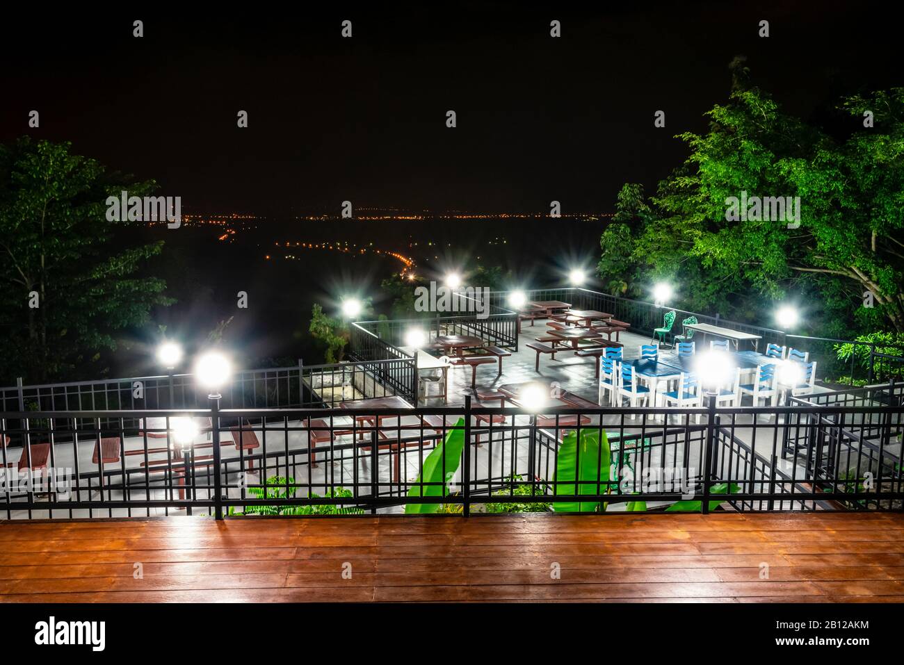 Nachtszene mit hohem Blickwinkel schöne Naturlandschaft und Straßenbeleuchtung in der Nacht. Tischstühle und Lampe auf der Terrasse zum Abendessen der Res Stockfoto