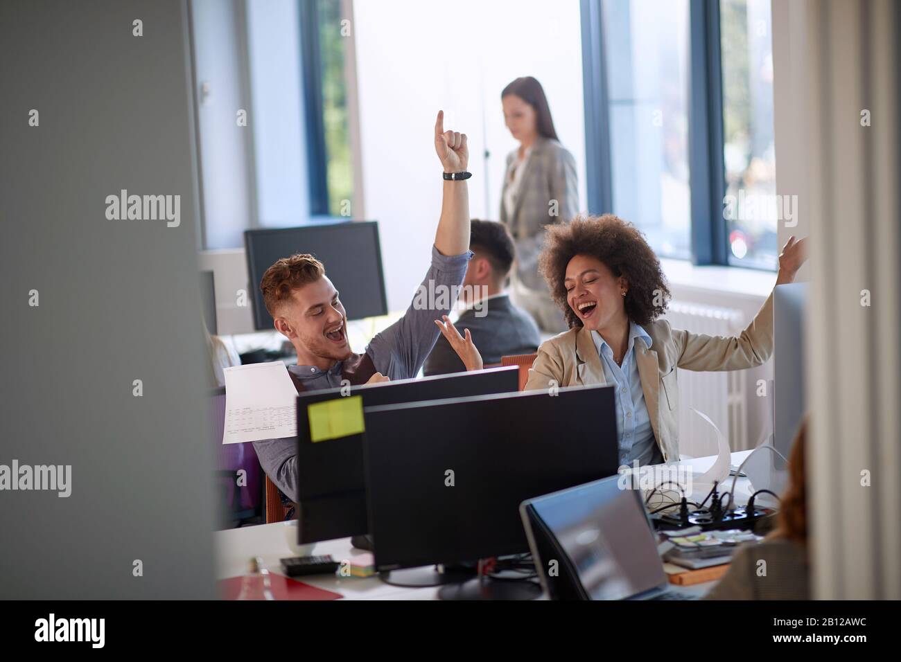 Glückliche Kollegen mit den Händen in der Luft, nachdem sie gute Geschäftsnachrichten erhalten haben: Positiv, glücklich, Gefühle, Erfolgskonzept Stockfoto