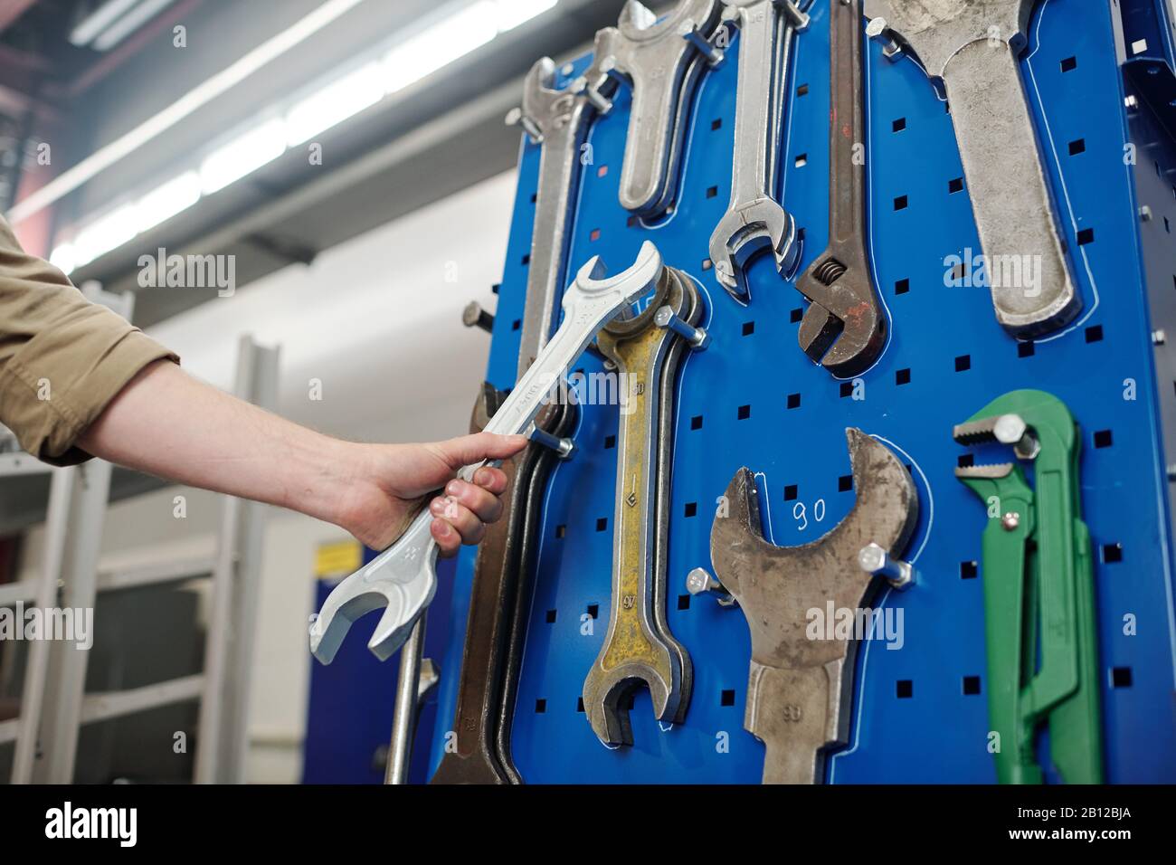 Hand des jungen Ingenieurs oder eines anderen Mitarbeiters der Industrieanlage, der einen großen Schraubenschlüssel hält Stockfoto